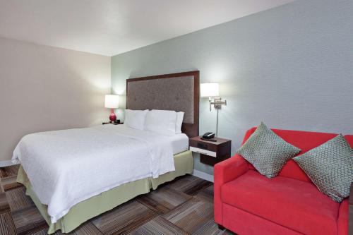 Habitación de hotel con cama y sofá rojo en Hampton Inn Los Angeles/Arcadia, en Arcadia