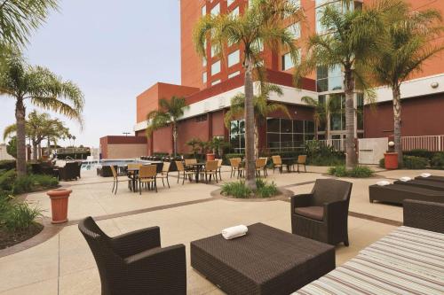 a patio with tables and chairs and palm trees at Embassy Suites by Hilton Anaheim South in Anaheim