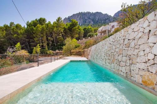 een zwembad naast een stenen muur bij Villa estilo Mediterráneo in Calpe