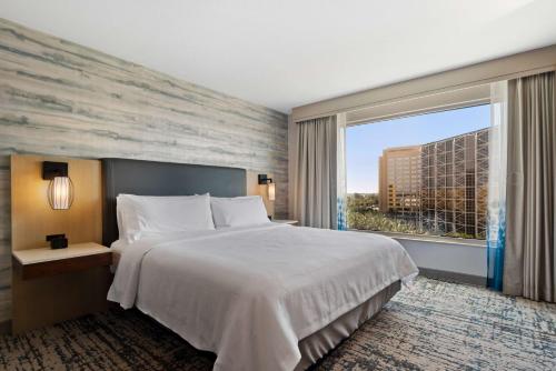 a bedroom with a large bed and a large window at Embassy Suites by Hilton Anaheim South in Anaheim