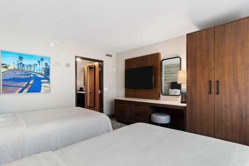 a hotel room with two beds and a desk and a tv at Embassy Suites by Hilton Anaheim South in Anaheim