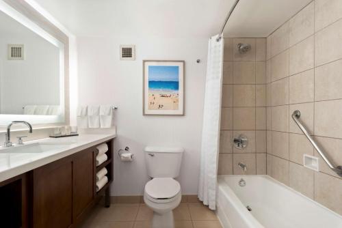 a bathroom with a toilet and a sink and a bath tub at Embassy Suites by Hilton Anaheim South in Anaheim