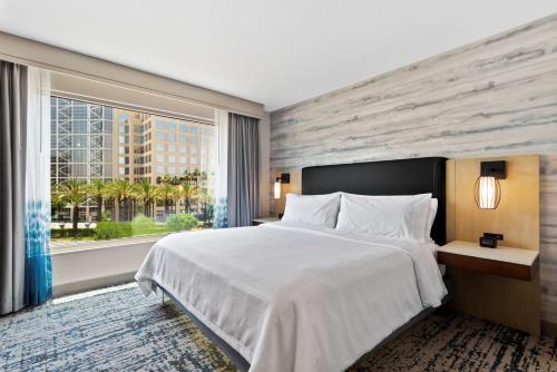 a bedroom with a large bed and a large window at Embassy Suites by Hilton Anaheim South in Anaheim