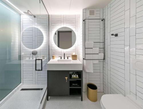 a bathroom with a sink and a shower and a mirror at The Wayfarer Downtown LA, Tapestry Collection by Hilton in Los Angeles