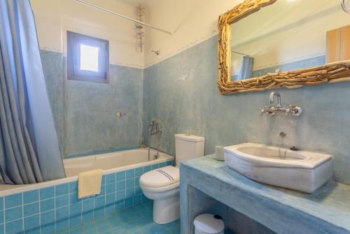 ein Badezimmer mit einem Waschbecken, einem WC und einem Spiegel in der Unterkunft Panormos Villas Collection in Panormos