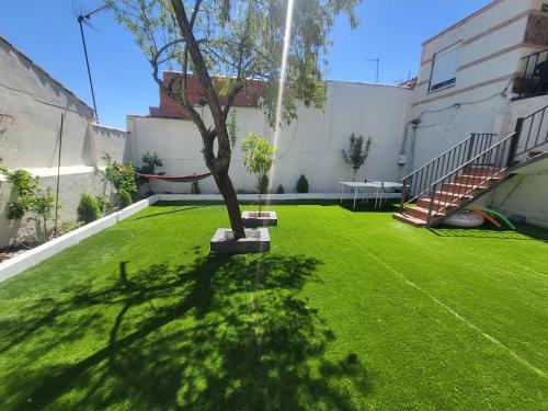 a green yard with a tree in the middle of it at Casa Oasis Puertollano, una casa rural en Puertollano, agradable, con Piscina en zona tranquila in Puertollano