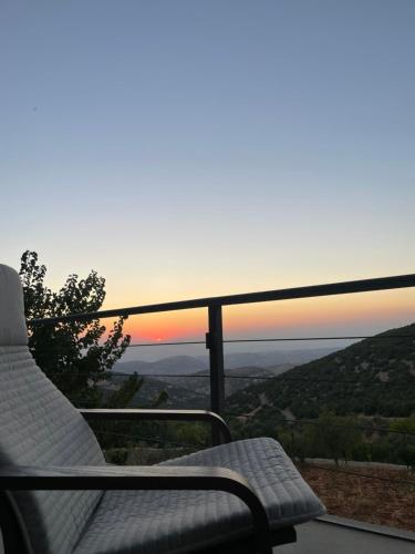 a balcony with a chair and a sunset in the background at Shams Farm in Ajloun