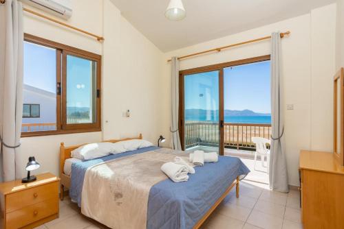 1 Schlafzimmer mit 2 Betten und einem Balkon in der Unterkunft Blue Bay Villas Collection in Mavroli