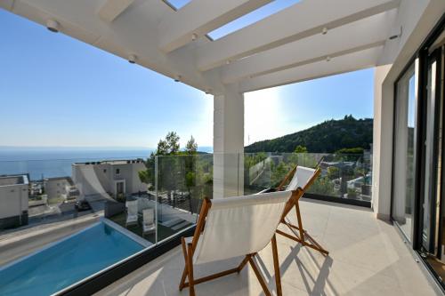 a white chair sitting on a balcony next to a pool at Villa Rosemary West in Makarska