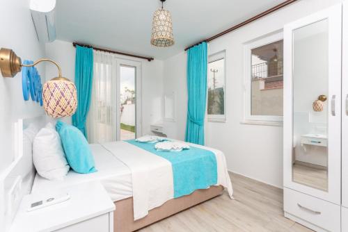 a white bedroom with blue curtains and a bed at Villa Portakal Blossom in Dalyan
