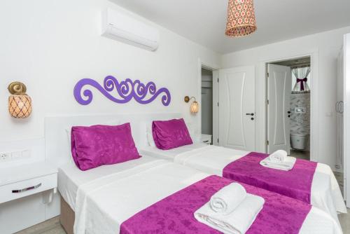 a white bedroom with a large bed with purple sheets at Villa Portakal Blossom in Dalyan
