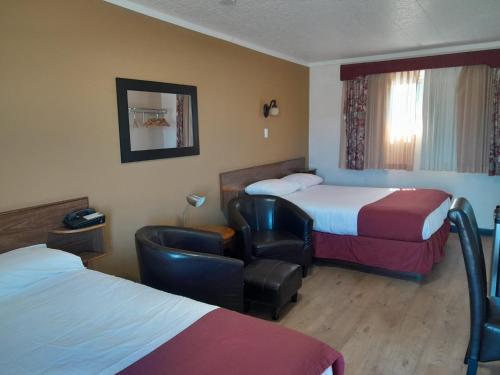 a hotel room with two beds and a chair at Travellers Motel in Cranbrook