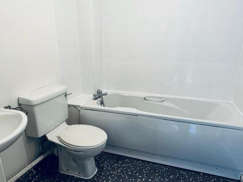 a white bathroom with a toilet and a bath tub at NANCY 1 in Portsmouth