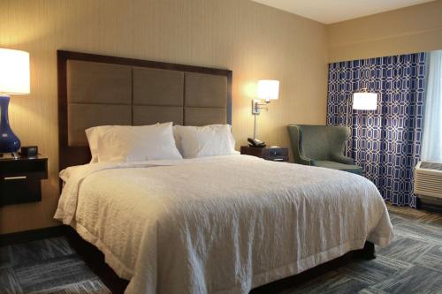 um quarto de hotel com uma cama grande e uma cadeira em Hampton Inn Lexington Medical Center, KY em Lexington
