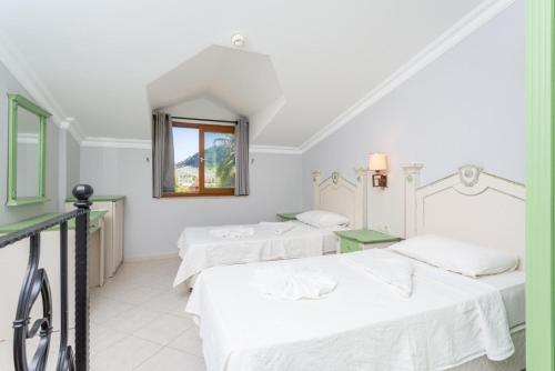 two beds in a white room with a window at Villa Ayla Paradise in Dalyan