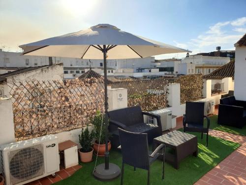 eine Terrasse mit einem Sonnenschirm, Stühlen und einem Tisch in der Unterkunft Entre patios y flores in Córdoba