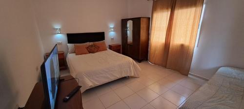 1 dormitorio con 1 cama y TV. en Monte Pissis ARG Departamento en Alquiler Temporario en San Fernando del Valle de Catamarca