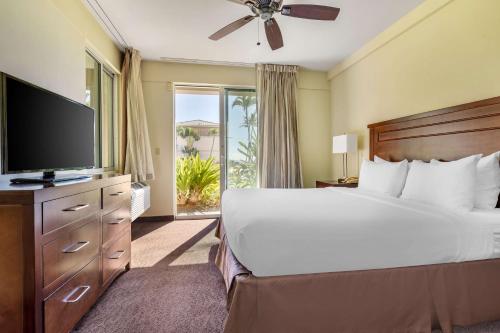 a bedroom with a large bed and a flat screen tv at Hilton Vacation Club The Point at Poipu Kauai in Koloa
