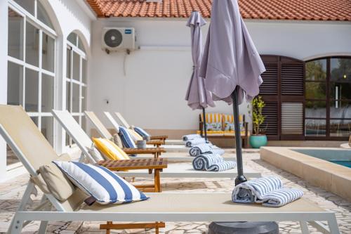 grupa krzeseł i parasol obok basenu w obiekcie Quinta do Quartel w mieście Évora