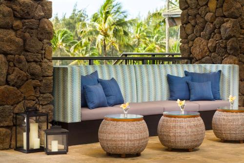 a patio with a couch with blue pillows and candles at Hilton Garden Inn Kauai Wailua Bay, HI in Kapaa