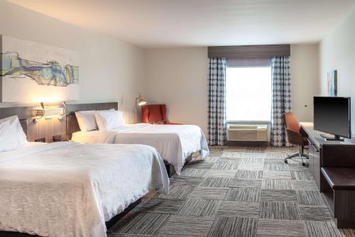 a hotel room with two beds and a flat screen tv at Hilton Garden Inn North Little Rock in North Little Rock
