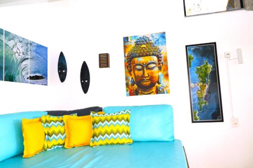 a blue couch in a room with paintings on the wall at Casas Temporada Aldeia Niura Opy in Florianópolis