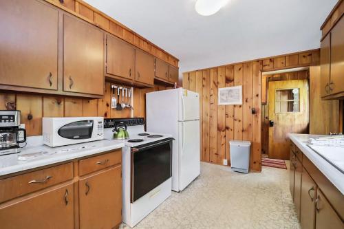 a kitchen with wooden cabinets and a white refrigerator at The Summer Cabin in Interlochen