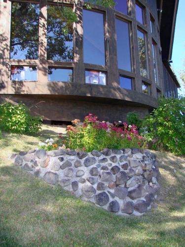 une maison avec un parterre de fleurs en pierre devant elle dans l'établissement Eagle's Nest Resort, à Anahim Lake