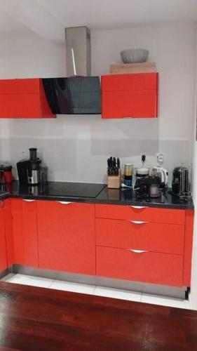 a kitchen with red cabinets and a black counter top at Jolie petite maison tout équipée in Le Gosier