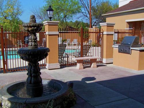 a black fountain in front of a fence with a bench at Homewood Suites Laredo at Mall Del Norte in Laredo
