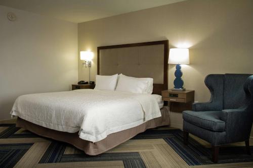 a hotel room with a bed and a blue chair at Hampton Inn and Suites La Crosse Downtown in La Crosse