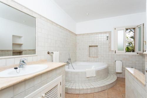 La salle de bains blanche est pourvue d'une baignoire et d'un lavabo. dans l'établissement Villa La Torre, à Alcúdia