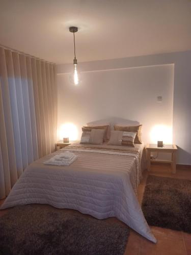 - une chambre avec un grand lit blanc et deux lampes dans l'établissement Refugio do Alviela, à Amiães de Baixo