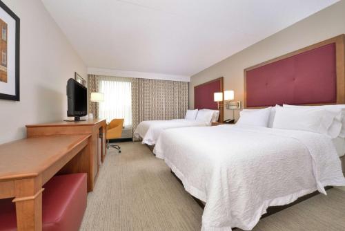 a hotel room with two beds and a flat screen tv at Hampton Inn Martinsburg in Martinsburg