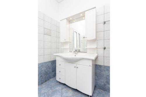 bagno con lavandino bianco e specchio di Villa Europe Thia a Fokáta