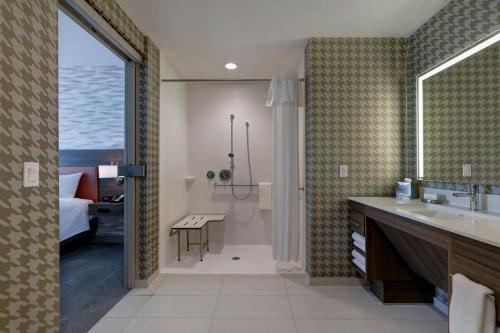 a bathroom with a sink and a shower and a bedroom at Home2 Suites By Hilton Turlock, Ca in Turlock