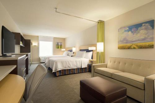 Home2 Suites By Hilton Leavenworth Downtown في ليفنورث: غرفه فندقيه بسرير واريكه