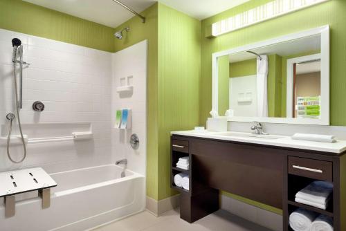 a bathroom with a tub and a sink and a mirror at Home2 Suites By Hilton Leavenworth Downtown in Leavenworth