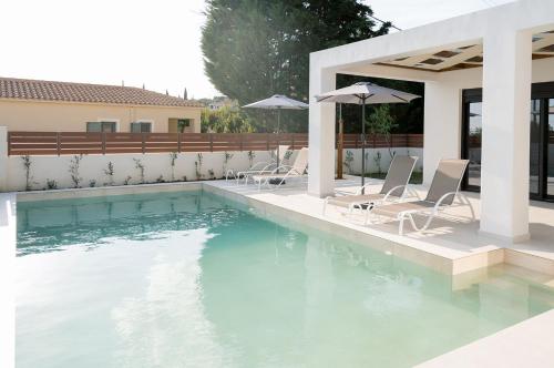 a pool with chairs and umbrellas next to a house at Villa Petra in Trapezaki