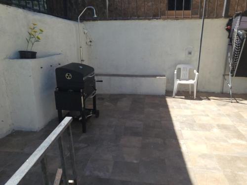 a room with a grill and a white chair at Casa Oasis Puertollano, una casa rural en Puertollano, agradable, con Piscina en zona tranquila in Puertollano