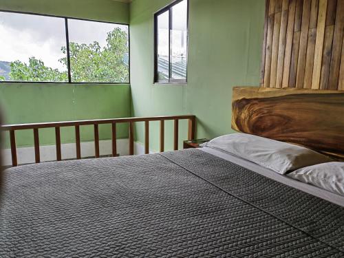 - une chambre avec un lit avec une tête de lit en bois et 2 fenêtres dans l'établissement Monteverde Monte Green, à Monteverde Costa Rica