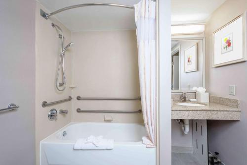 Baño blanco con bañera y lavamanos en Hilton Garden Inn Independence en Independence