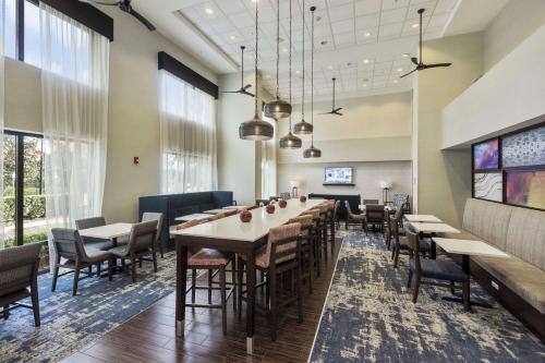 un comedor con mesas, sillas y ventanas en Hampton Inn & Suites Orlando-Apopka en Orlando