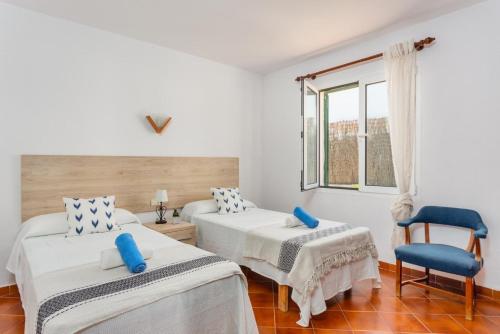 um quarto com 2 camas e uma cadeira em Villa Miguels em Es Mercadal