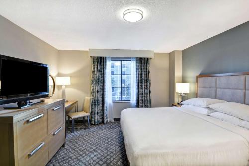 a hotel room with a bed and a flat screen tv at Embassy Suites by Hilton Orlando Downtown in Orlando