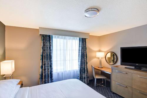 a hotel room with a bed and a desk and a television at Embassy Suites by Hilton Orlando Downtown in Orlando