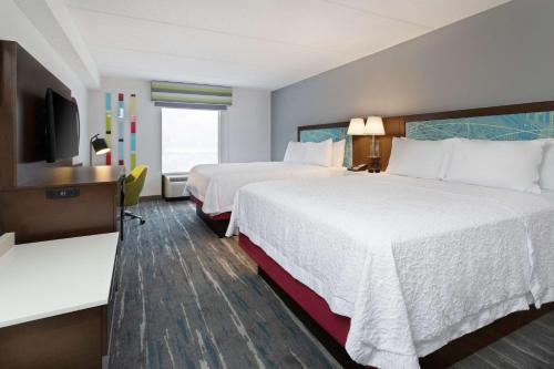 a hotel room with two beds and a flat screen tv at Hampton Inn & Suites Orlando International Drive North in Orlando