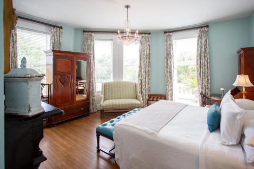 a bedroom with a bed and a chair and windows at Kehoe House, Historic Inns of Savannah Collection in Savannah