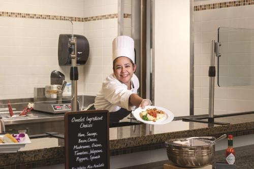a chef holding a plate of food in a kitchen at Embassy Suites by Hilton Orlando Lake Buena Vista South in Kissimmee