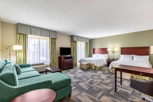 a hotel room with two beds and a couch at Hampton Inn & Suites Orlando-South Lake Buena Vista in Kissimmee